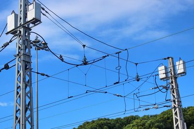 Low angle view of electricity pylon against blue sky