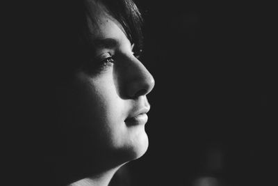 Close-up of young woman against black background