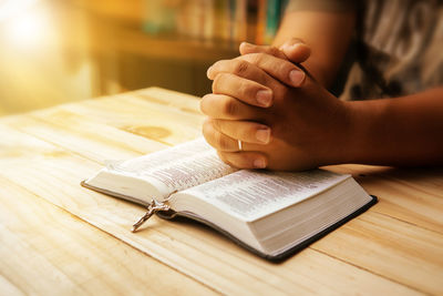 Midsection of woman reading bible at table