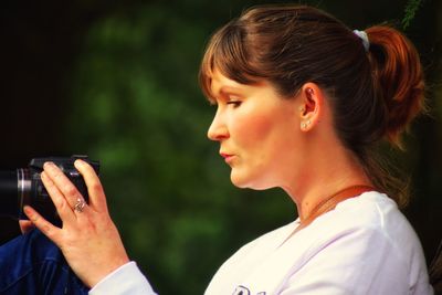 Side view of woman using dslr camera