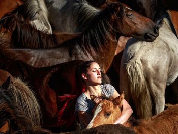 High angle view of mid adult woman embracing horse at stable