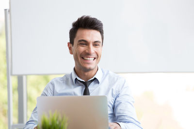 Cheerful businessman looking away while working in office