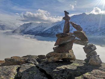 Stack of rock on snowcapped mountain against sky