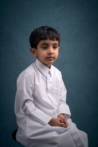 Portrait of boy standing against gray background