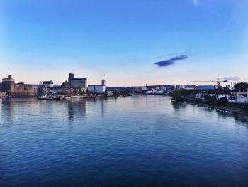 Scenic view of river by buildings against blue sky