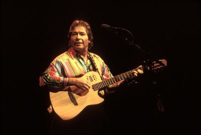 Man playing guitar against black background