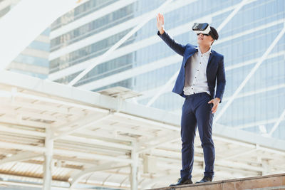 Businessman wearing virtual reality simulator against office building