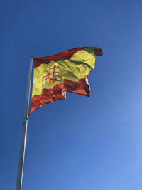 Low angle view of flag against clear blue sky