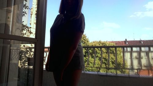 Rear view of woman standing against window