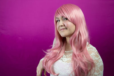 Portrait of young woman against pink background