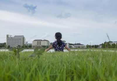 Man sitting on field against sky