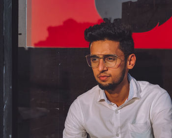 Portrait of young man standing against wall