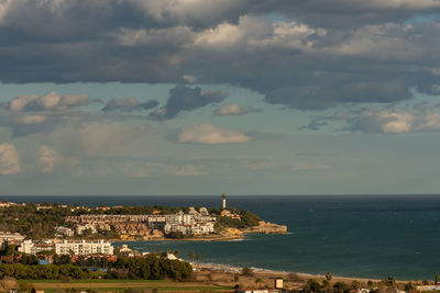 Aerial view of townscape by sea against sky