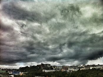 Buildings in city against storm clouds