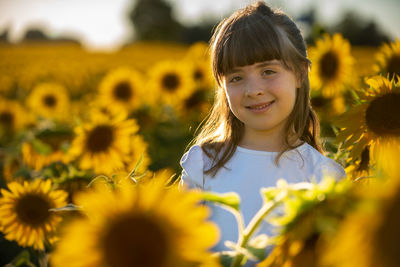 Portrait of smiling girl against blue yellow flowering plants