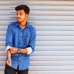 Portrait of young man looking away against wall