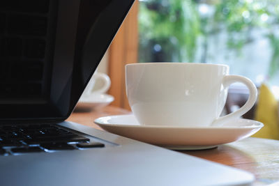 Close-up of laptop and coffee cup on table