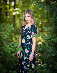 Young woman standing against plants