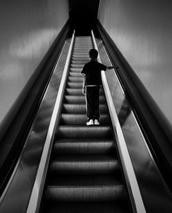 Rear view of boy standing on escalator