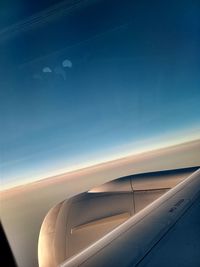 Airplane wing against sky during sunset