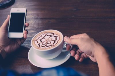 Midsection of woman holding coffee cup on table