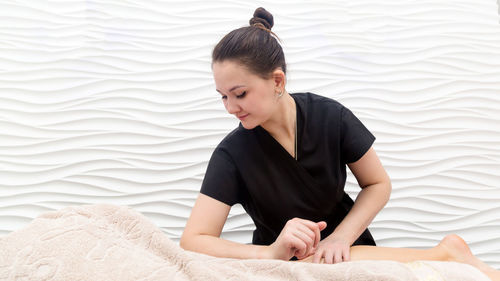 Young woman looking away while sitting on bed