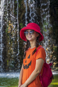 Portrait of smiling woman standing against waterfall