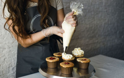 Midsection of woman holding ice cream on table