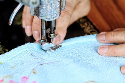 Cropped hand of tailor using sewing machine