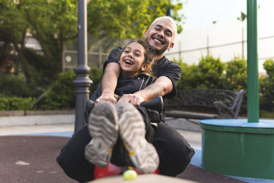 Cheerful father and daughter playing together at park