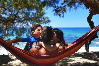 Father with children relaxing in hammock at beach