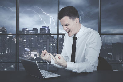 Angry businessman using laptop in office