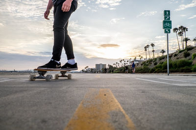 Low section of man skateboarding on road