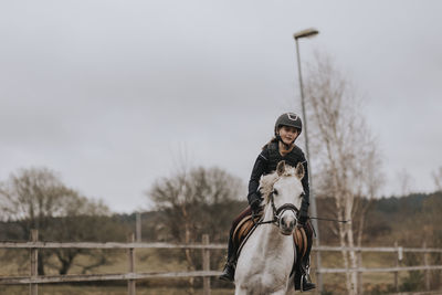 View of girl horseback riding