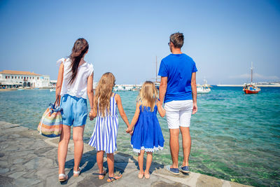 Rear view of friends standing by sea against sky