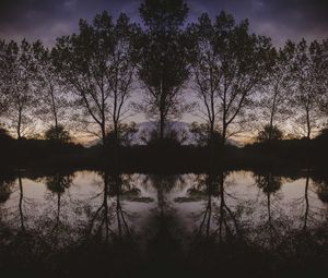 Silhouette trees by lake against sky at sunset