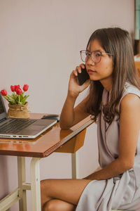 Young woman using mobile phone while sitting at home