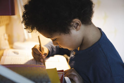 Boy writing in book while doing homework