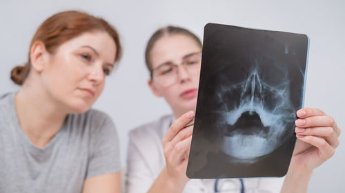 Portrait of woman using digital tablet while standing against white background