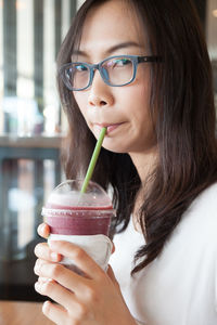 Close-up portrait of young woman drinking smoothie