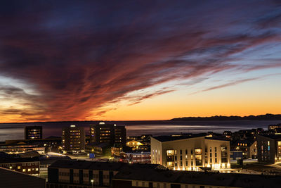 Illuminated cityscape against sky during sunset