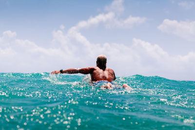 Shirtless man surfing on sea against sky