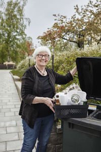 Smiling senior woman carrying recycling rubbish