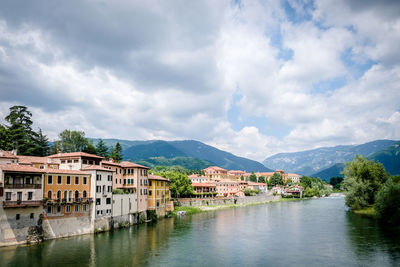 Buildings by lake against sky