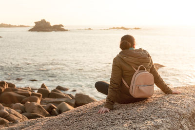 Woman sits relaxed at sunset, on the coast. ribeira, galicia, spain