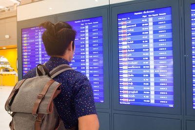 Man with backpack looking at text on device screen in airport