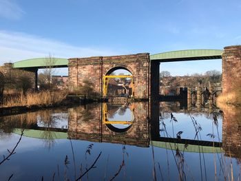Reflection of built structure in water against clear blue sky