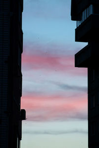 Low angle view of silhouette buildings against sky at sunset