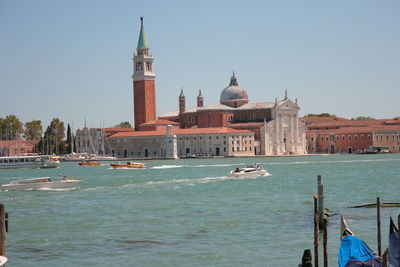 Boats in canal amidst buildings against clear sky