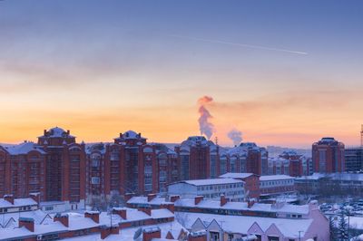 High angle view of buildings in city against orange sky during winter